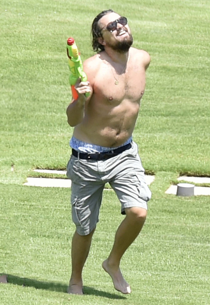 Leonardo DiCaprio playing with a water gun running and laughing